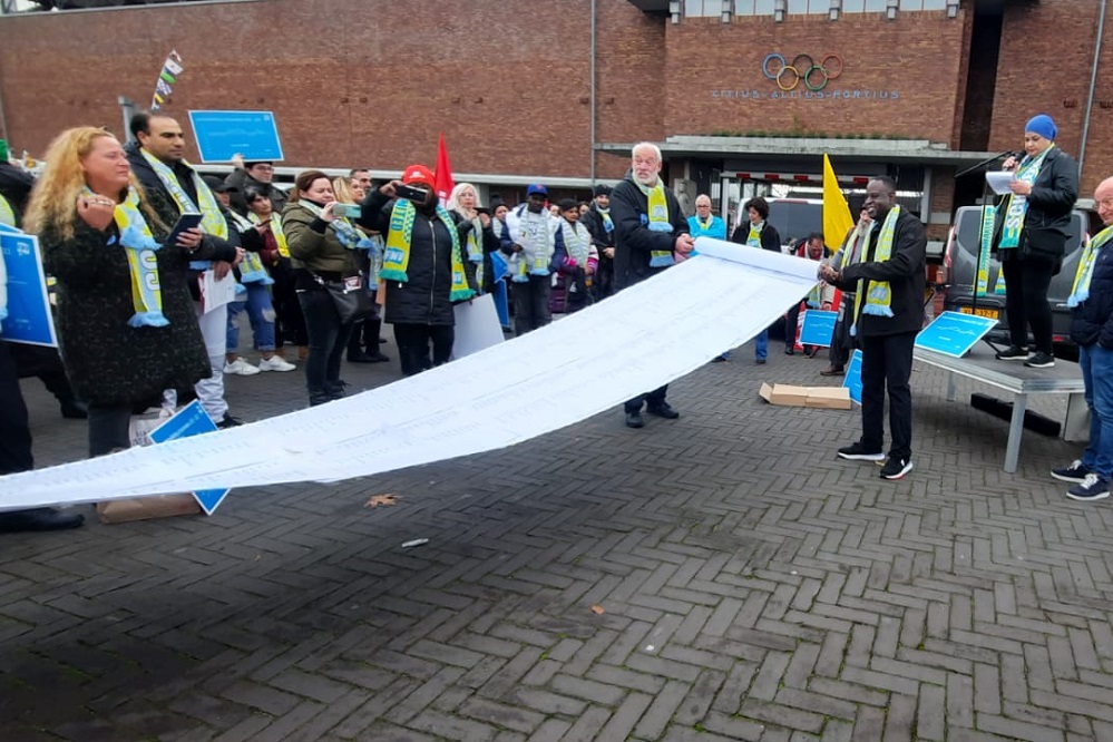 Voor de poorten van het Olympisch Stadion in Amsterdam voerden de schoonmakers op zaterdag 25 november jongstleden een gemoedelijke actie voor extra loon, of we hun wensen tot het maken van een boven-cao afspraak kracht bij te zetten. De leden van FNV Schoonmaak , mede namens CNV Vakmensen , boden Rob Westerlaken van Schoonmakend Nederland een petitie aan, die de werkgeversvertegenwoordiger in ontvangst heeft genomen. In deze petitie vragen de bonden aan de werkgevers om aan tafel te gaan voor een collectieve compensatie van de hoge inflatie. Westerlaken toonde begrip voor de situatie en heeft toegezegd dat de werkgevers dit gesprek aangaan met de bonden. Een extra compensatie zal ongetwijfeld effect hebben op de toch al forse aankomende prijsstijging. Wie betaalt uiteindelijk de rekening? Schoonmakend Nederland: cao wordt ingehaald door werkelijkheid Schoonmakend Nederland heeft de petitie van FNV met de oproep om aan tafel te gaan aanvaard. De woordvoerder: “De door de bond geschetste voorbeelden van medewerkers die de touwtjes niet meer aan elkaar kunnen knopen zijn herkenbaar. Die raken ons ook. En we zien ook dat de mooie cao die we vorig jaar met elkaar hebben afgesproken, wordt ingehaald door de werkelijkheid met hoge inflatie en hoge energiekosten.” Het is volgens Schoonmakend Nederland goed te zien dat de schoonmaak werkgevers individueel collega’s in nood volop te hulp schieten: ” Met het verstrekken van voorschotten, overnemen van schulden, de inzet van budgetcoaches, enzovoort… We moedigen onze leden ook aan dit te blijven doen. De problemen verschillen per medewerker sterk (thuissituatie, uren werk, soort energiecontract). De werkgevers springen daar snel en goed op in binnen hun mogelijkheden. Hiervoor bieden we vanuit de branche ook handvatten.” Tegelijkertijd heeft de overheid naar de mening van Schoonmakend Nederland een fors pakket maatregelen afgekondigd die de schoonmakers echt gaan helpen, zoals het energieplafond, verhoging huur- en zorgtoeslag en huurverlaging. “We moeten ook kijken naar de andere kant: onze ondernemers en hun opdrachtgevers krijgen ook wat voor de kiezen de komende tijd: neem de hoge inflatie; ondernemers merken dat ook in hun eigen bedrijf. De reiskostenbudgetten voor 2022 waren deze zomer al verbruikt bijvoorbeeld. Ook is het zo dat de kabinetsmaatregelen voor koopkrachtcompensatie in 2023 betaald worden door lastenverzwaring bij bedrijven. En zoals het er nu uitziet moeten we serieus rekening houden met een recessie.” Kortom, het zijn bijzondere tijden voor medewerkers en ondernemers: “Hierover gaan we uiteraard in gesprek. De petitie van FNV is inmiddels in het bezit van het bestuur en de datum om aan tafel te gaan staat.” FNV : er moet echt iets gebeuren Het door werkgeversvertegenwoordiger Rob Westerlaken getoonde begrip voor de situatie waarin de schoonmakers zich bevinden alsmede zijn toezegging om met de bonden rond te tafel te gaan wordt door de schoonmakers zeer gewaardeerd: FNV Schoonmaak bestuurder Renate Bos: “Het werd als een feestje gevierd binnen het schoonmaakparlement. Maar ook vernam ik geluiden in de trant van ”als we de cao een half jaar later afgesloten zouden hebben dan zou deze er volledig anders uit hebben gezien” of “door de flinke stijging van het minimum loon voelt het of we per 1 januari aanstaande minder gaan verdienen”. De verwachtingen op extra compensatie door de werkgevers zijn dan ook hoog onder de schoonmakers. Begin december volgt het eerste gesprek. Renate Bos: “De nood van schoonmakers is heel hoog, er moet echt iets gebeuren.” CNV: geen pleister plakken Bestuurder Jan Kampherbeek is in ieder geval tevreden over de erkenning van het probleem door Schoonmakend Nederland:” De hoge inflatie wordt nu door sommige bedrijven op individueel niveau op de een of andere manier gecompenseerd. Dat is mooi. Het is echter belangrijk dat er een collectieve regeling getroffen wordt. Geen pleister plakken en maar dan maar hopen dat het bloeden stopt, maar de wond goed bekijken en dan een adequate genezingswijze toepassen.” Kampherbeek wacht de uitkomsten van de AWVN af over welke effecten/maatregelen de overheidsmaatregelen hebben op de diverse cao’s: ”Aan de hand van deze uitkomsten kunnen we bepalen wat een redelijke compensatie voor de schoonmakers vanuit de werkgeverszijde is. Hierbij denken we niet aan een éénmalige compensatie, die je momenteel bij bedrijfstakken ziet, maar voor de schoonmaak denk ik in de breedte.” SIEV: spagaat Werkgeversorganisatie SIEV hield aangaande de bereidheid tot extra looncompensatie een flitsenquête onder haar leden. De reacties stromen binnen. Voorzitter Raymond Kouwenberg: “Uit de tot dusverre ontvangen reacties merk ik het spanningsveld onder de leden. Als sociale ondernemers begrijpen ze de problematiek en is er de bereidheid tot compensatie. De marges in de schoonmaak zijn echter dusdanig klein, dat er nauwelijks ruimte is zonder de gezonde bedrijfsvoering in gevaar te brengen. Met andere woorden er zal vanuit de opdrachtgevers de bereidheid moeten bestaan om dit mede te financieren danwel zijn er belastingmaatregelen nodig om de bruto-netto verhouding aantrekkelijker te maken. Dan kunnen we wellicht een deel van de vakantietoeslag en/of vakantiedagen omzetten in loon of iets dergelijks.” De voorzitter pleit ervoor dat de bonden samen met de werkgeversorganisatie en de RAS de opdrachtgevers ervan te overtuigen dat een verdere kostenstijging onafwendbaar is. Complexe materie Als gevolg van de bestaande cao afspraken in samenhang met de inflatie en de forse stijging van energiekosten is de verwachting dat de prijsaanpassing binnen de schoonmaaksector flink hoger zal zijn dan het jarenlang het geval was. Ons rondje langs de velden bevestigt dit vermoeden . Als er daarenboven sprake is van een verdere looncompensatie zal de prijsaanpassing verder omhoog schieten. Uiteraard is het fijn als de schoonmakers de waardering voor hun vak terugzien in de loonhoogte. De vraag werpt zich wel op wat een stevige prijsaanpassing impliceert voor onder meer de werkdruk (m2 prestatie), schoonmaak frequenties etc. indien de opdrachtgevers zoeken naar mogelijkheden om deze kostenstijging in het absolute bedrag te matigen. Kortom eeen complexe materie, die de nodige vragen oproept. Wat betekent dit voor de huishoudelijke hulpen in de privésector? Zal het zwartwerken in dit segment toenemen? Zal het inbesteden van de schoonmaak toenemen? Wie betaalt uiteindelijke de rekening? De werkgevers, overheid of opdrachtgevers?